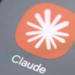 A smartphone displaying the Claude AI app interface on its home screen, with an Android phone and an iPhone placed side by side.